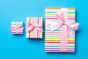 wrapped Christmas or other holiday handmade present in paper with pink ribbon on blue background. Present box, decoration of gift on colored table, top view photo