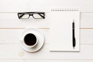 Modern office desk table with notebook and other supplies with cup of coffee. Blank notebook page for you design. Top view, flat lay photo