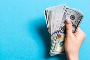 Top view of female hand holding a pack of one hundred dollar bills on colorful background. Wage and salary concept with empty space for your design photo