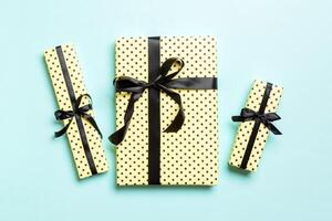 wrapped Christmas or other holiday handmade present in paper with Black ribbon on blue background. Present box, decoration of gift on colored table, top view photo