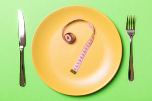Question mark made of measuring tape on round plate on green background. Top view of hesitation and diet concept photo