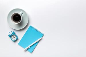 Modern office desk table with notebook and other supplies with cup of coffee. Blank notebook page for you design. Top view, flat lay photo