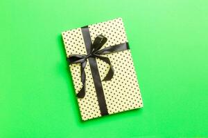 Top view Christmas present box with black bow on green background with copy space photo