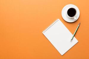 Modern office desk table with notebook and other supplies with cup of coffee. Blank notebook page for you design. Top view, flat lay photo