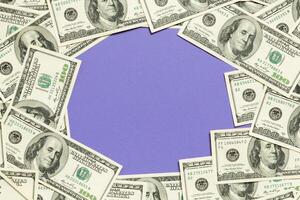 Frame made of dollars with copy space in the middle. Top view of business concept on purple background with copy space photo