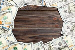 Frame of one hundred dollar bills with empty space for your design. Top view of business concept on dark wooden background with copy space photo