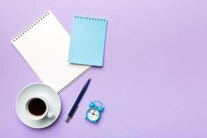 Modern office desk table with notebook and other supplies with cup of coffee. Blank notebook page for you design. Top view, flat lay photo