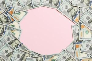 Frame of one hundred dollar bills with empty space for your design. Top view of business concept on pink background with copy space photo