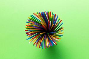 Top view of many multicolored plastic cocktail tubes in a glass. Drinking straws of bright colors Isolated on white background photo