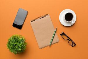 Modern office desk table with notebook, smartphone and other supplies with cup of coffee. Blank notebook page for you design. Top view, flat lay photo