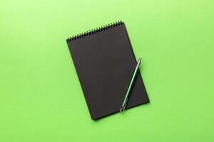 school notebook on a colored background, spiral black notepad on a table Top view photo