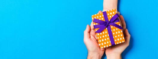 Top view of a woman and a man giving and receiving a present on colorful background. Love and relationship concept. Copy space photo