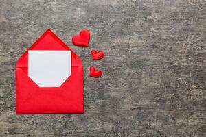 Red paper envelope with empty white card and heart on colored background. top view valentines day concept photo
