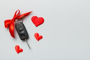 Car key with a red bow and a heart on Colored table. Giving present or gift for valentine day or christmas, Top view with copy space photo