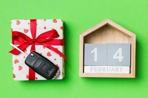 Top view of car key on a gift box with red hearts and festive calendar on colorful background. The fourteenth of february. Present for Valentine's Day concept photo