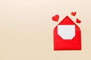Red paper envelope with empty white card and heart on colored background. top view valentines day concept photo
