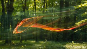 The blurred motion of a kite flying through a green forest its long tail leaving a streak of color in its path photo