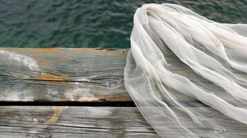 Soft delicate fabric brushes against the rough aged wood of the floating dock the meeting of two contrasting textures photo