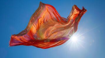 The gentle breeze causes a floating sari to sway revealing intricate details and pops of bright color against a clear blue sky photo
