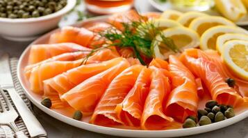 A platter of smoked salmon flaky and delicate served with a side of lemon wedges and capers photo