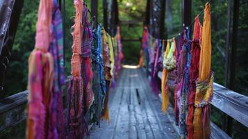Vibrant fabric pieces hanging from the sides of a bridge seem to be reaching out and embracing the natural elements around them photo