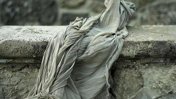 The fabric of a tattered old tunic sways odically in the wind dd over a stone bench that has been worn smooth by time photo