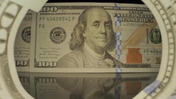 das Kamera Pfannen durch aufgerollt hundert Dollar Rechnungen. das Rechnungen sind im Fokus, mit das Porträt von Benjamin Franklin prominent angezeigt im das Center. video