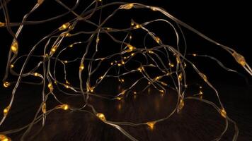 A string of copper wire lights, with small yellow bulbs, is draped across a wooden surface. The lights are on and illuminating the dark background. video