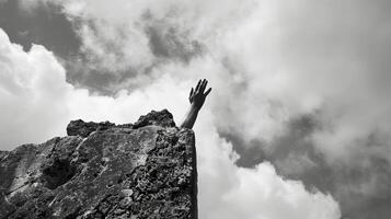 A solitary hand emerging from a block of stone reaching towards the sky. Black and white art. photo