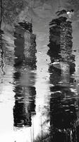 A distorted reflection of city buildings on the mirrored surface of a river. Black and white art. photo