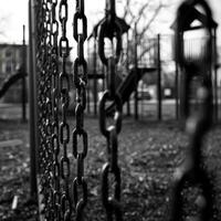 A rusty fence with missing sections surrounds a neglected playground once a source of joy for children in this decaying neighborhood. Black and white art. photo