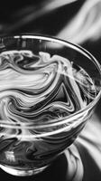 A closeup shot of a glass cup filled with espresso the swirling patterns of the coffee and the reflections creating an abstractart.t piece. Black and white art. photo
