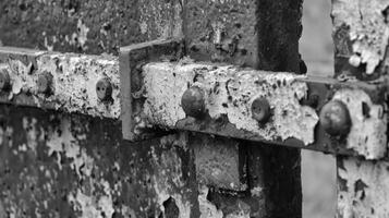 The rough and jagged edges of a rusted metal gate no longer able to swing open with ease. Black and white art. photo