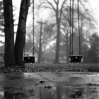 A rainsoaked playground with empty swings swaying in the wind. Black and white art. photo