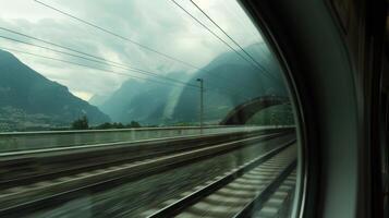 Through the trains window a view of the mountain landscape can be seen as it emerges from the tunnel photo
