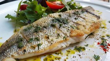 A delicate and buttery sea bass seasoned with foraged herbs and served with a side of sea lettuce salad photo