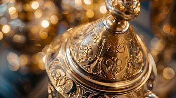 A closeup of a goldplated cocktail shaker ornately detailed with intricate designs and a round handle that adds a touch of elegance to any bar cart photo