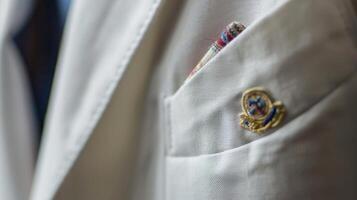 A closeup of a white blazer showcases the intricate design of the clubs emblem with colorful threads carefully stitched onto the pocket. The crisp clean lines of the blazer give of photo