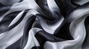 A closeup image of a silk scarf adorned with a bold abstract pattern in shades of black white and grey. The fluidity of the silk fabric allows the intricate design to pop in all it photo