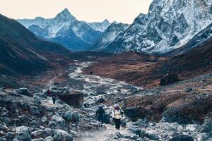 Group of trekkers trekking in Himalayas mountains through Cho la glacier and pass. to Gokyo Ri. Nepalese male guide leading tourist client in Sagarmatha national park official trek photo