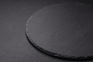 Empty round slate plate for template on the black background photo