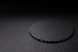 Empty round slate plate for template on the black background photo
