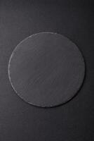 Empty round slate plate for template on the black background photo
