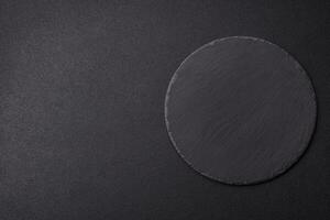 Empty round slate plate for template on the black background photo