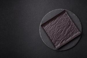 Empty round slate plate for template on the black background photo