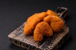 Delicious fresh crispy chicken nuggets on a dark concrete background photo