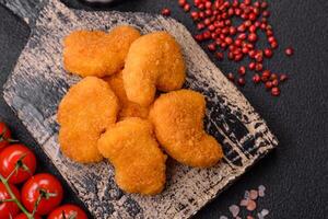 Delicious fresh crispy chicken nuggets on a dark concrete background photo