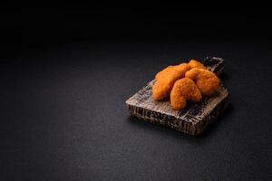 Delicious fresh crispy chicken nuggets on a dark concrete background photo