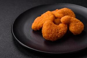 Delicious fresh crispy chicken nuggets on a dark concrete background photo