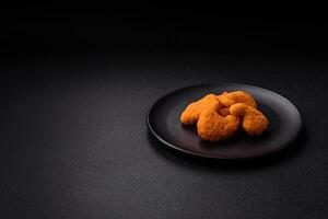 Delicious fresh crispy chicken nuggets on a dark concrete background photo